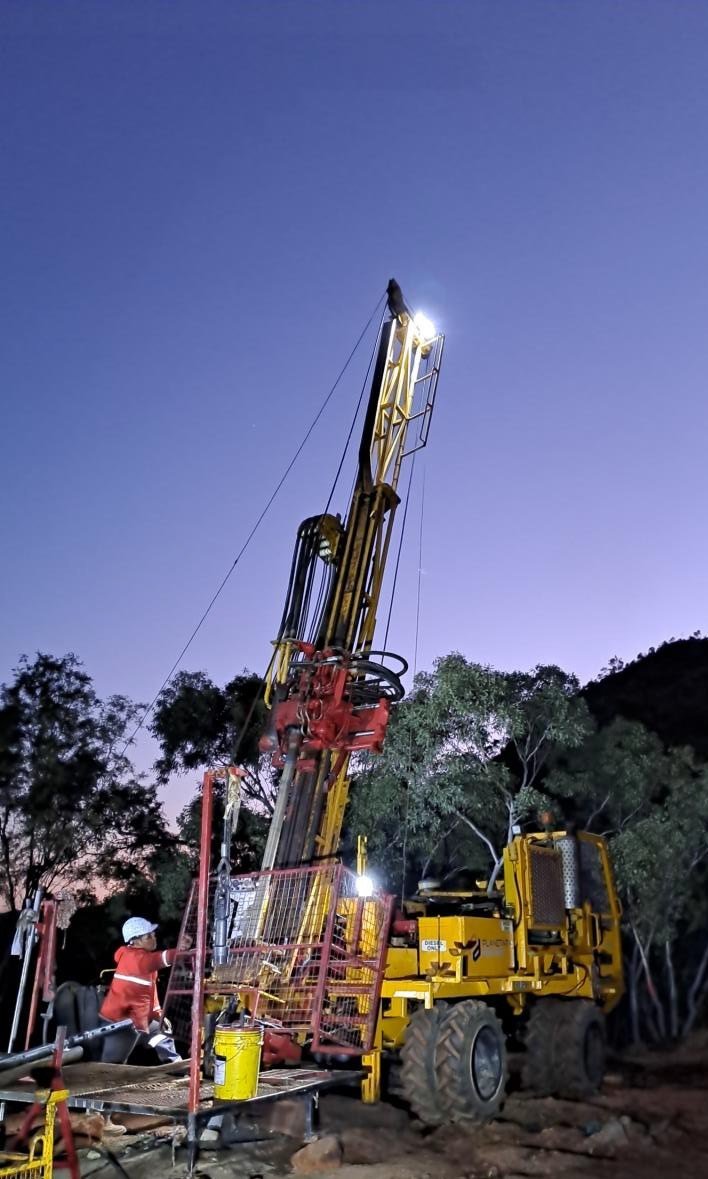 Track-mounted diamond drill rig operating at dusk on a uranium program in Queensland, Australia